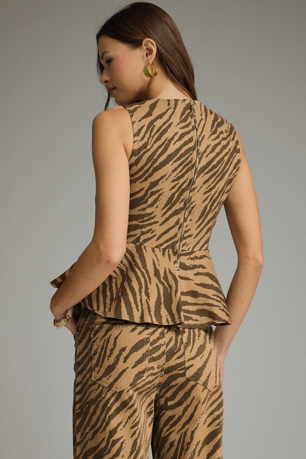 A bold zebra print sleeveless top featuring a flattering peplum hem and tailored silhouette for effortlessly chic styling.