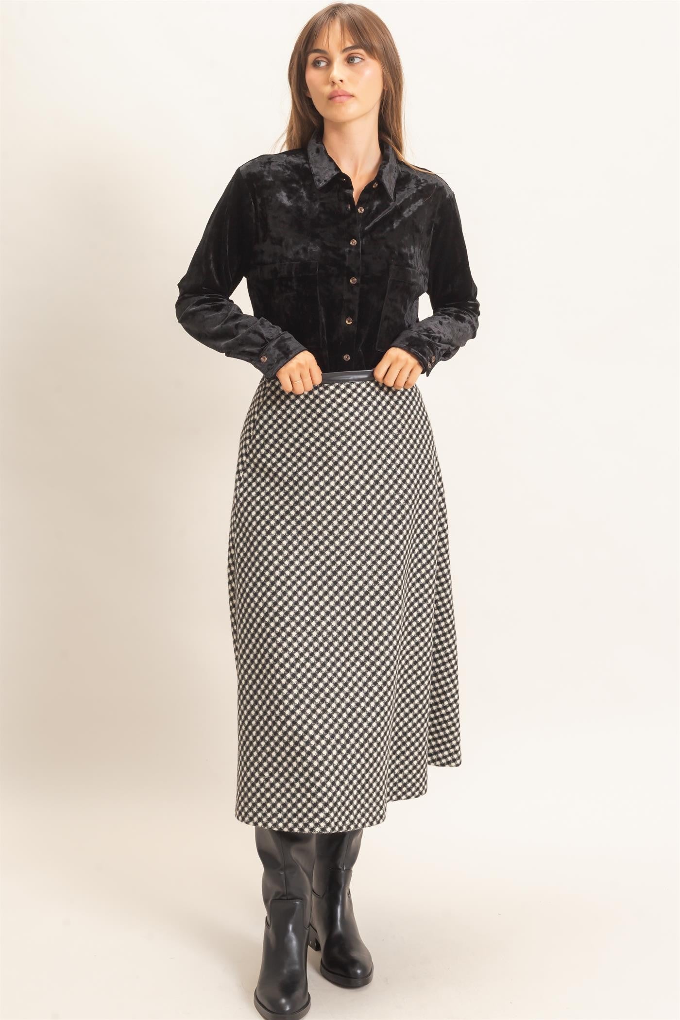 A sophisticated checkered A-line midi skirt featuring a sleek faux leather waistband and flattering flare for effortlessly polished style.
