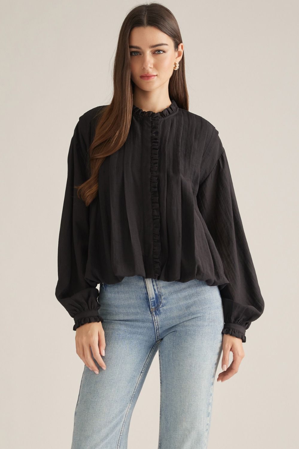A romantic long-sleeve blouse featuring a ruffled high neckline, delicate front ruffle trim, and elegant button details for a timeless feminine look.

