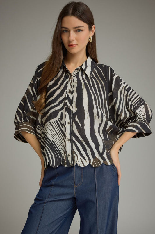 A bold and stylish zebra-print blouse featuring flowing poncho sleeves, a classic shirt collar, button-front closure, and a feminine scalloped hem.