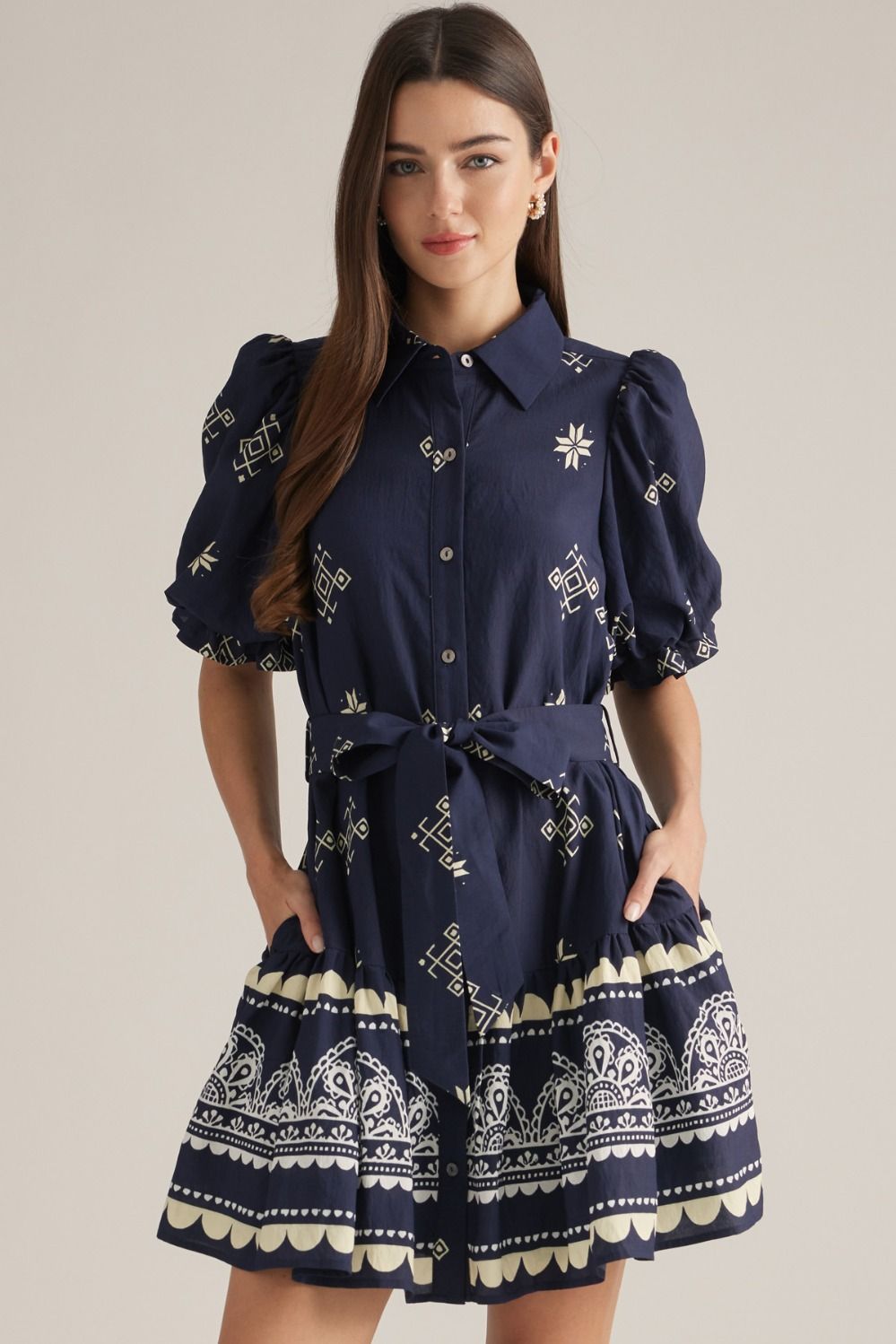 A charming printed mini dress featuring puff sleeves, a classic shirt collar, self-tie waist, and playful ruffle hem finished with a contrasting border print.