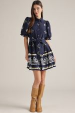 A charming printed mini dress featuring puff sleeves, a classic shirt collar, self-tie waist, and playful ruffle hem finished with a contrasting border print.