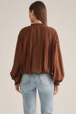 A romantic long-sleeve blouse featuring a ruffled high neckline, delicate front ruffle trim, and elegant button details for a timeless feminine look.

