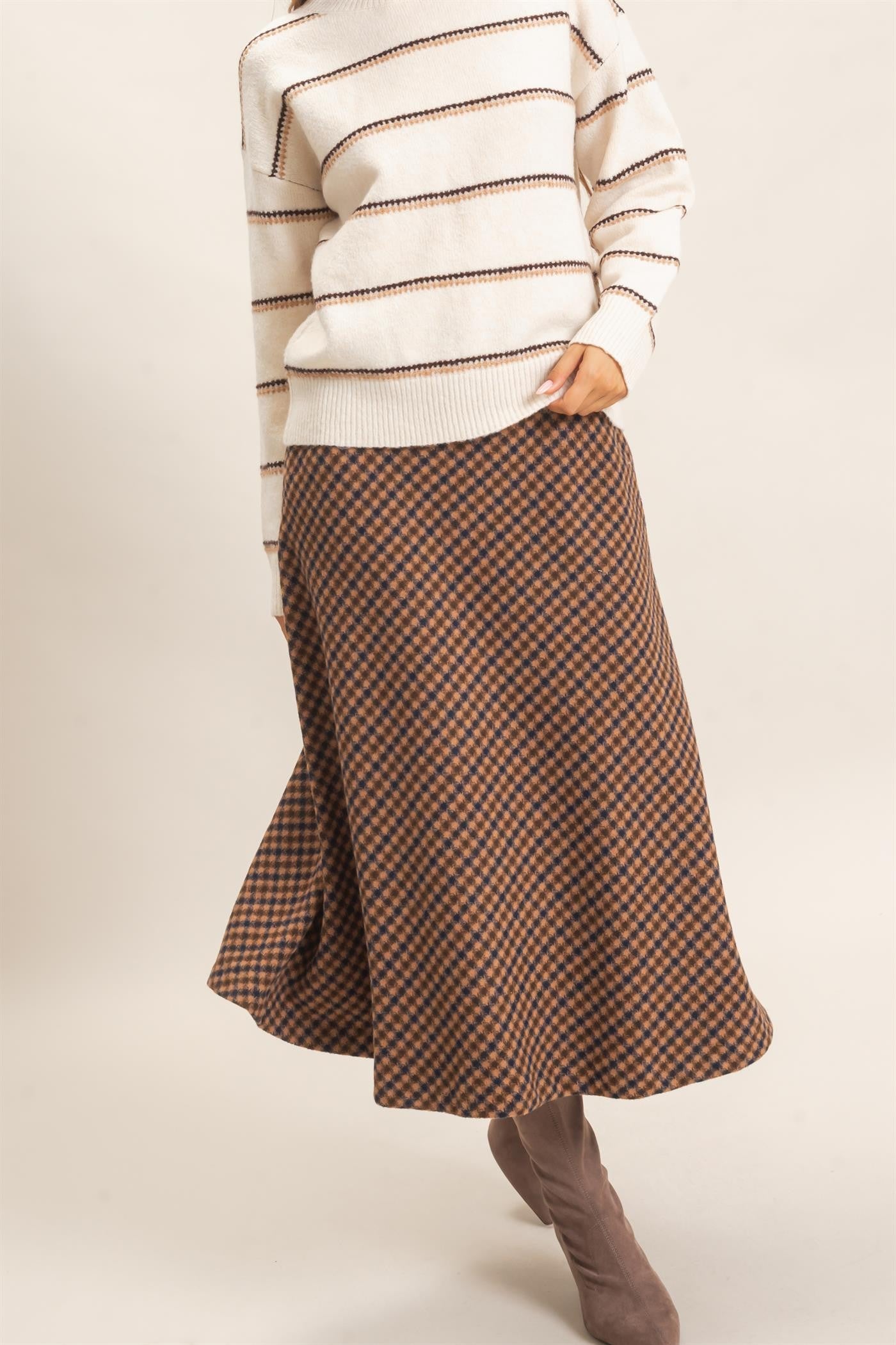 A sophisticated checkered A-line midi skirt featuring a sleek faux leather waistband and flattering flare for effortlessly polished style.
