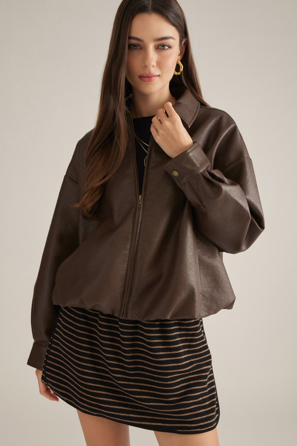 A sleek faux leather jacket featuring a classic shirt collar,bubble hem, front zipper, button cuffs, and practical side pockets for polished everyday style.