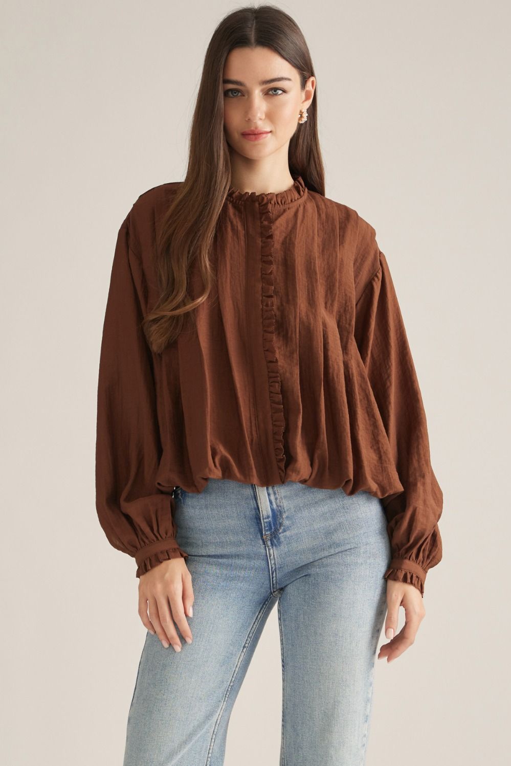 A romantic long-sleeve blouse featuring a ruffled high neckline, delicate front ruffle trim, and elegant button details for a timeless feminine look.


