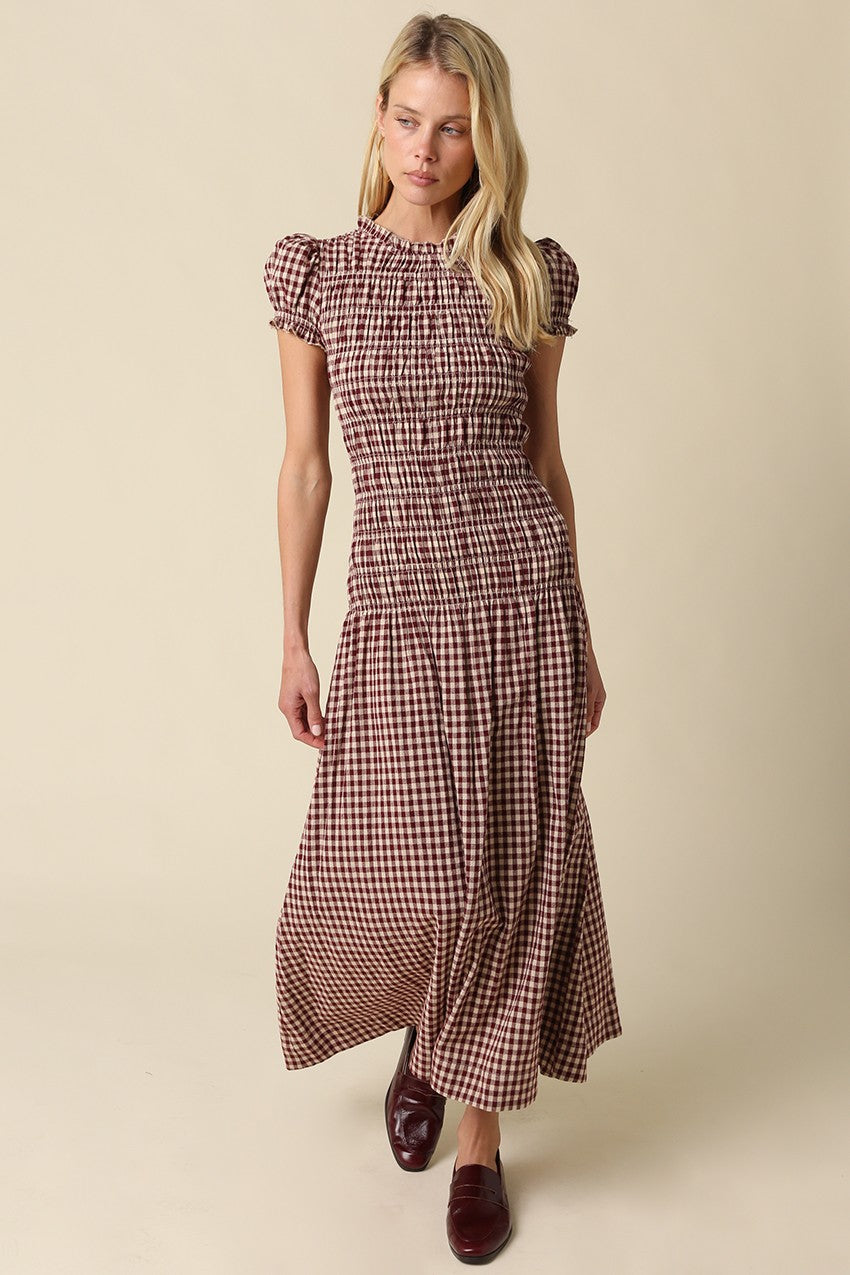 A romantic plaid maxi dress featuring soft puff sleeves, a fitted smocked bodice, and a flowing gathered skirt for an effortlessly feminine silhouette.