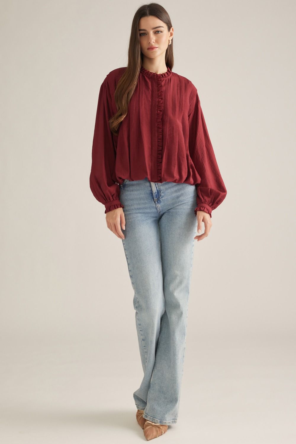 A romantic long-sleeve blouse featuring a ruffled high neckline, delicate front ruffle trim, and elegant button details for a timeless feminine look.

