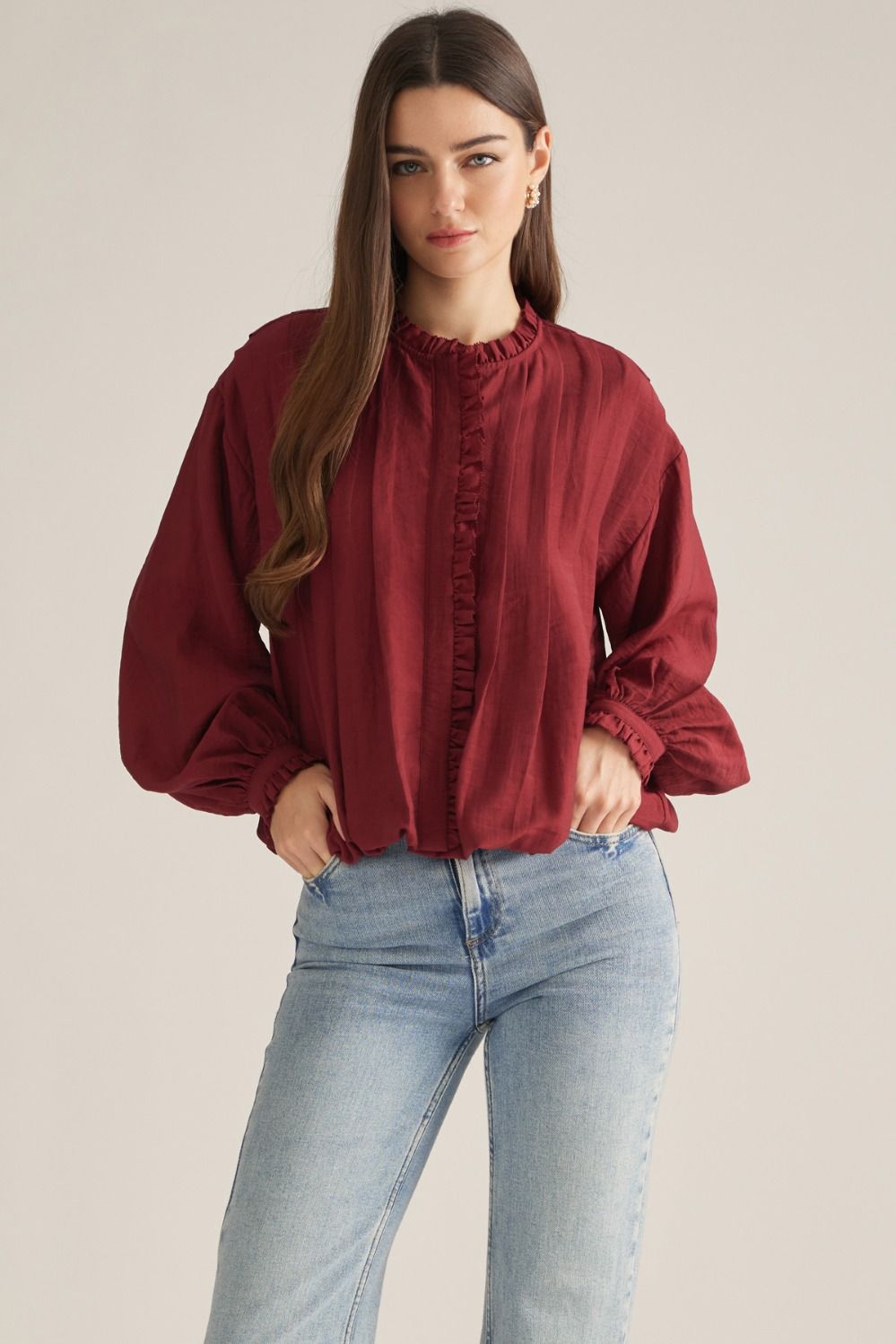 A romantic long-sleeve blouse featuring a ruffled high neckline, delicate front ruffle trim, and elegant button details for a timeless feminine look.

