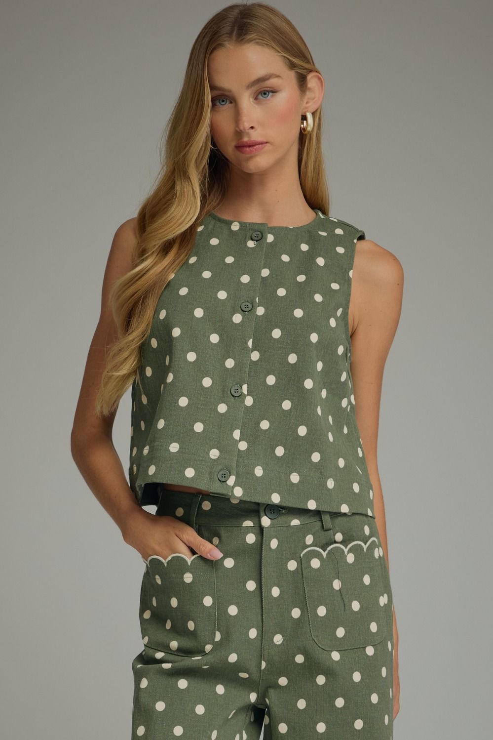 A timeless polka dot sleeveless top with a classic round neckline and button-front detail for effortless everyday style.
