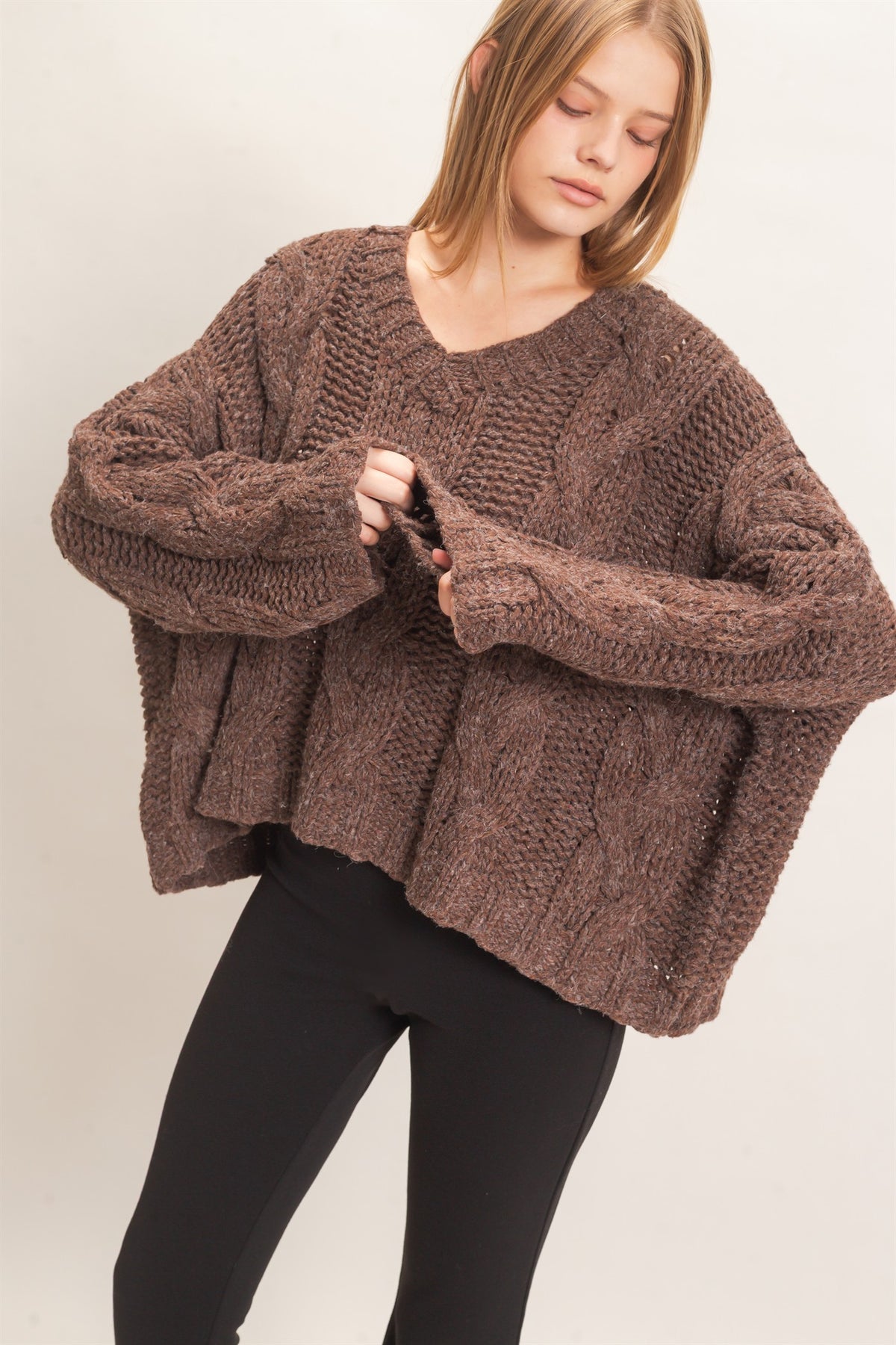 A cozy chunky-knit sweater featuring a classic V-neck, statement cable-knit detailing, relaxed drop shoulders, and a modern cropped hem.