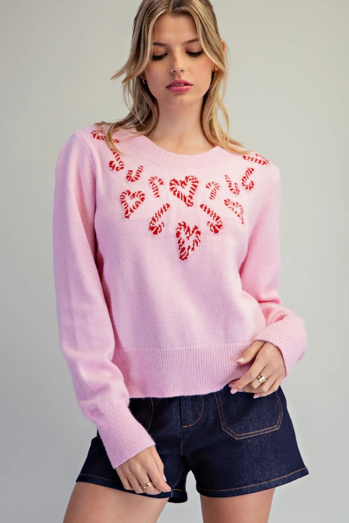 A cozy festive knit sweater featuring candy cane heart motifs, a classic crew neckline, and wide ribbed trims for a charming holiday look.