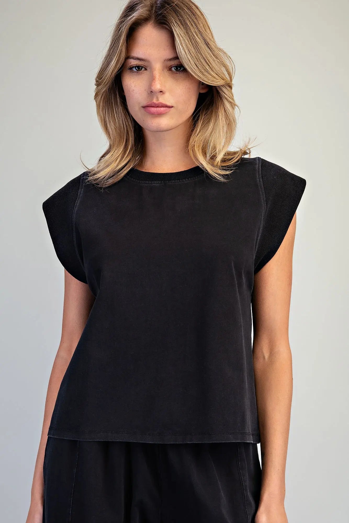 A relaxed washed top featuring structured cap shoulders, ribbed trim detailing, and a minimalist silhouette for effortless everyday style.