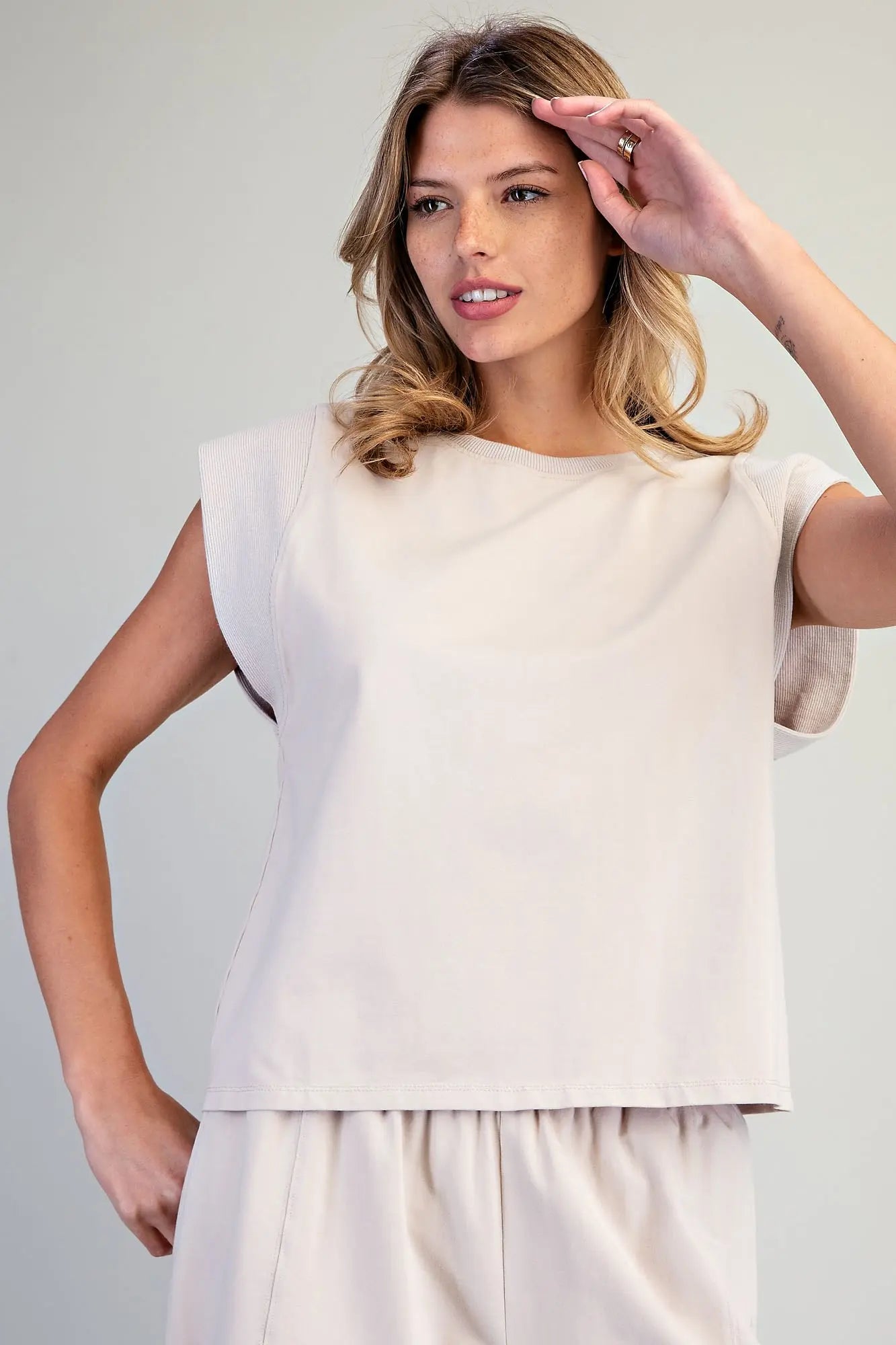 A relaxed washed top featuring structured cap shoulders, ribbed trim detailing, and a minimalist silhouette for effortless everyday style.
