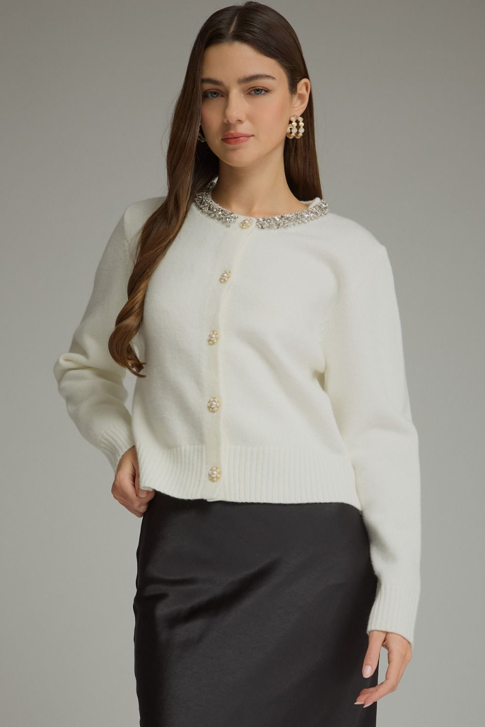 A polished knit cardigan featuring elegant rhinestone and pearl trim, pearl buttons, and classic ribbed details for a sophisticated feminine finish.