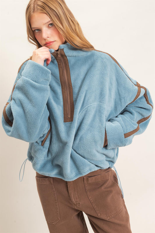 A cozy fleece pullover featuring a high funnel neck, sporty contrast trim, oversized curved pockets, and an adjustable drawstring hem.