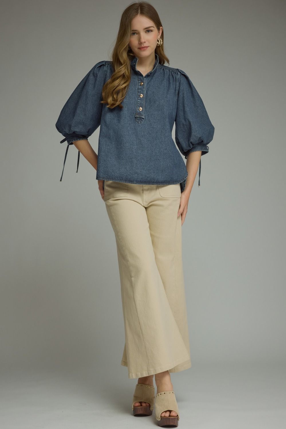 A feminine lightweight denim top featuring romantic ¾ puff sleeves, a classic button-front closure, and adjustable self-tie cuffs for a polished everyday look.