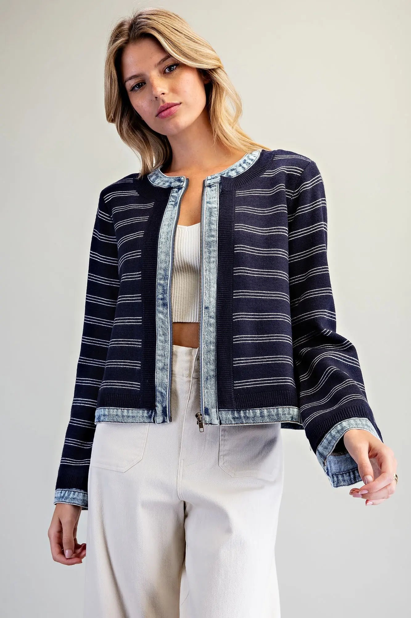 A casually chic striped knit jacket featuring contrasting washed denim trim, a zip-front closure, and a slightly cropped silhouette.
