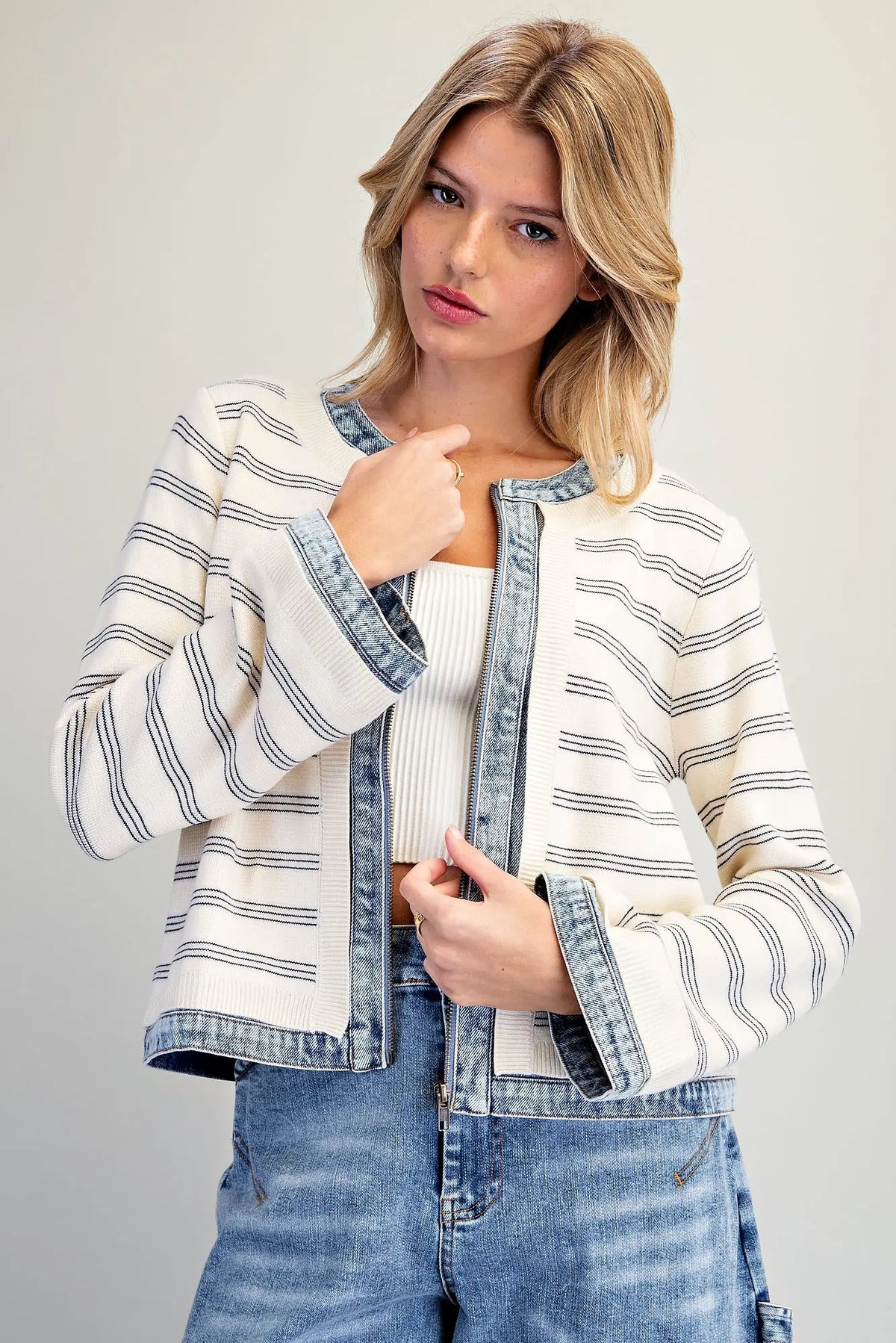 A casually chic striped knit jacket featuring contrasting washed denim trim, a zip-front closure, and a slightly cropped silhouette.
