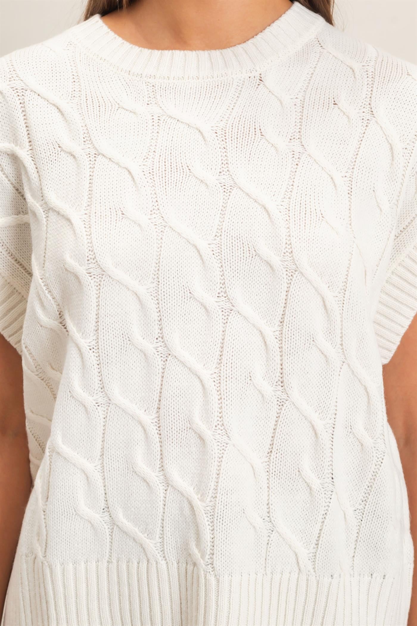 A timeless cable knit sweater featuring a classic crew neckline and cap sleeves for an effortlessly polished look you'll wear year-round.