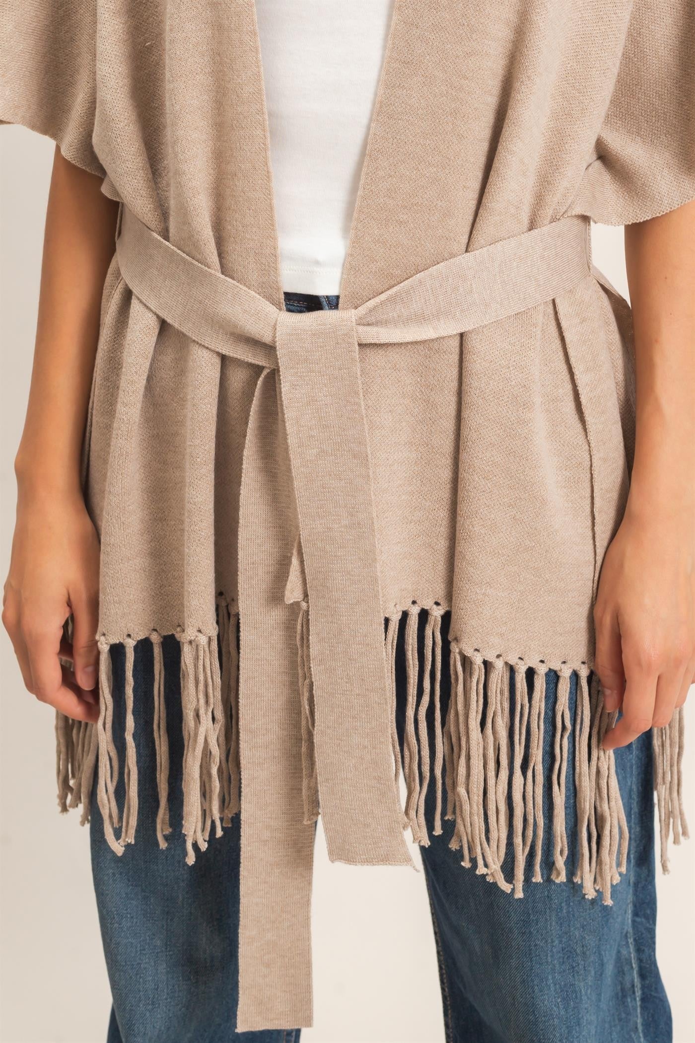 A chic open-front kimono sweater with wide sleeves, a self-tie waist, and statement fringe trim that adds effortless movement to any outfit.