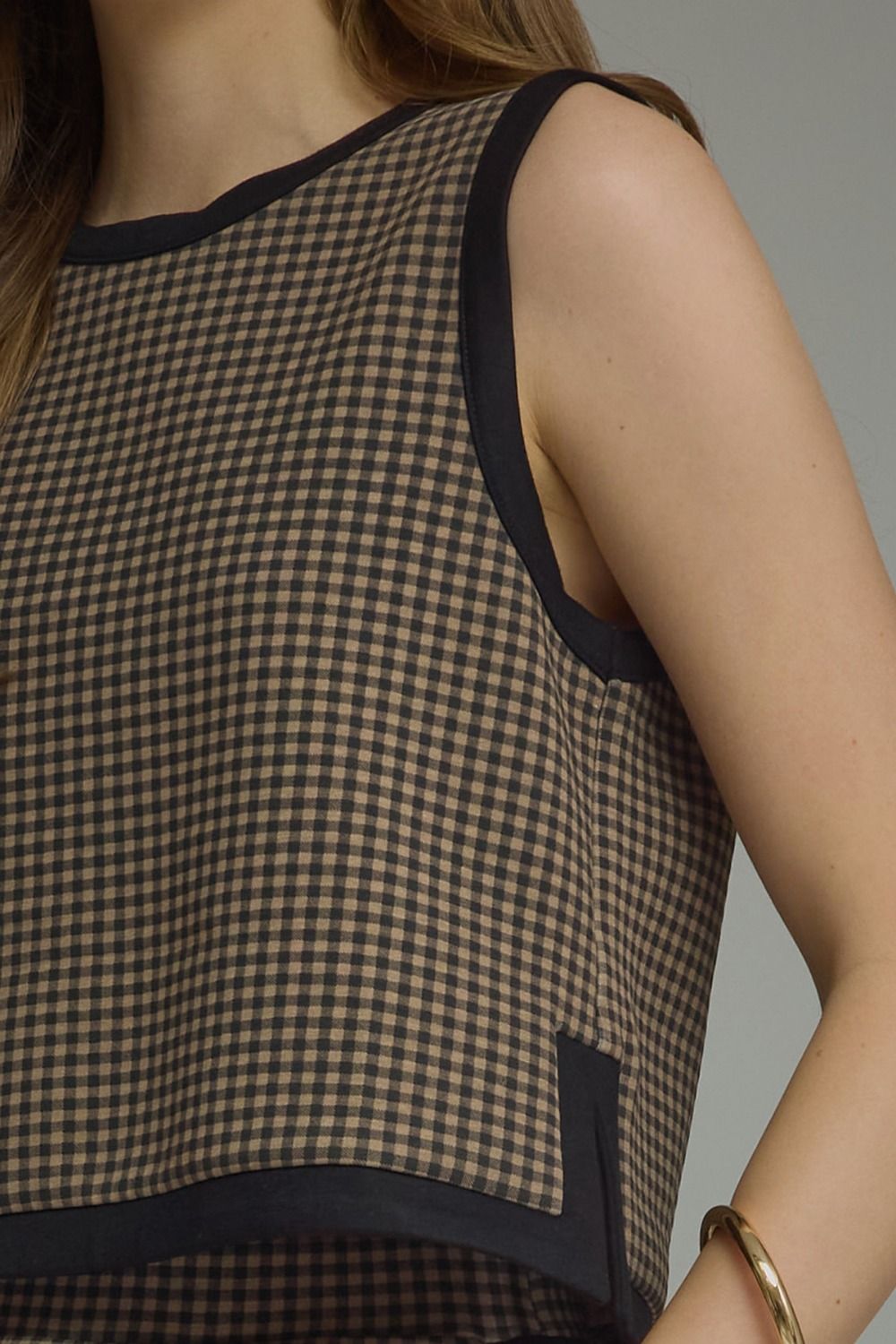 A charming gingham knit top featuring contrast binding, a layered hem, and a lightweight sleeveless silhouette perfect for effortless everyday style.