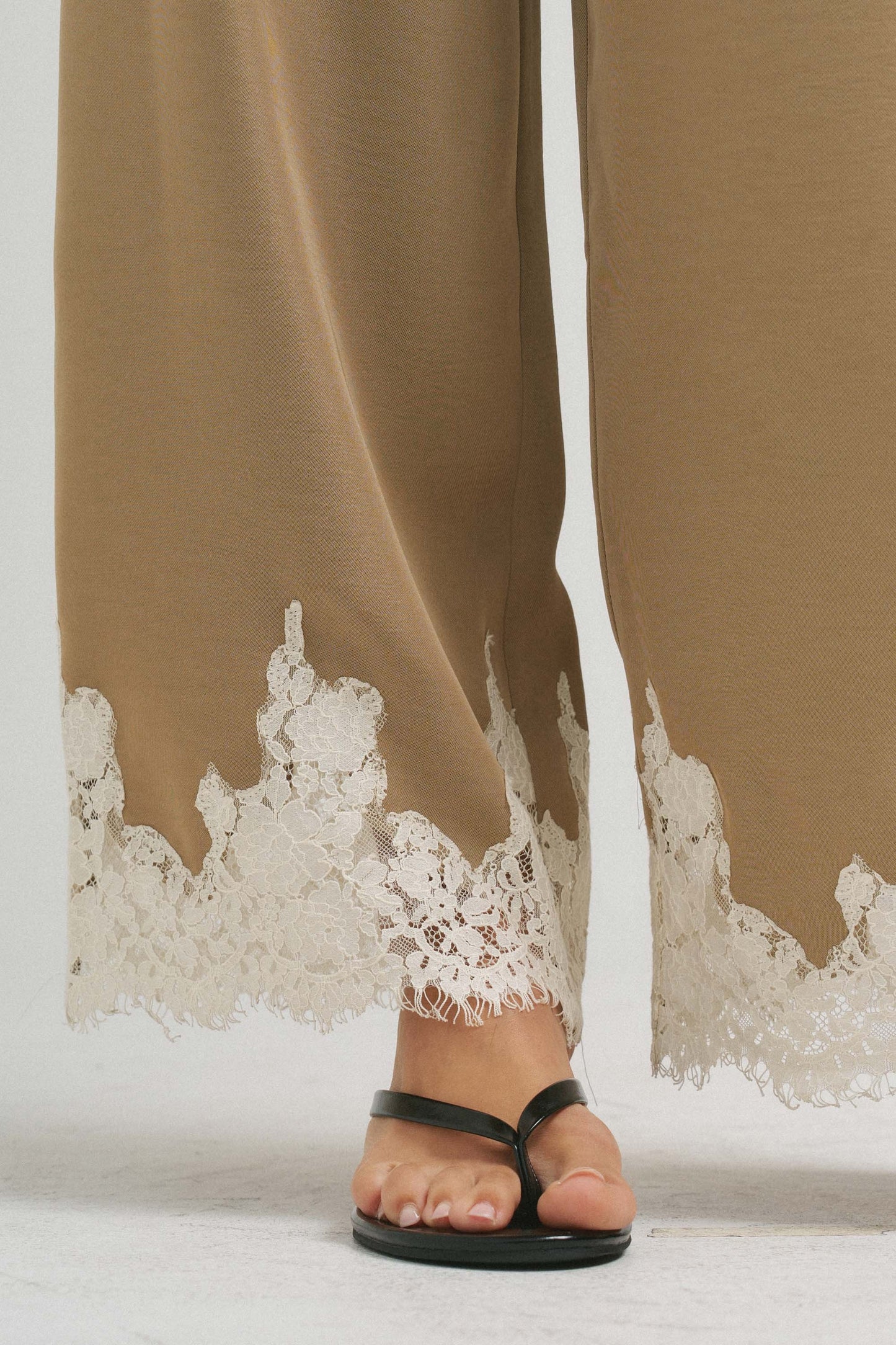 An effortlessly elegant two-piece set featuring delicate lace trim, a gathered neckline, and flowing wide-leg pants for timeless sophistication.
