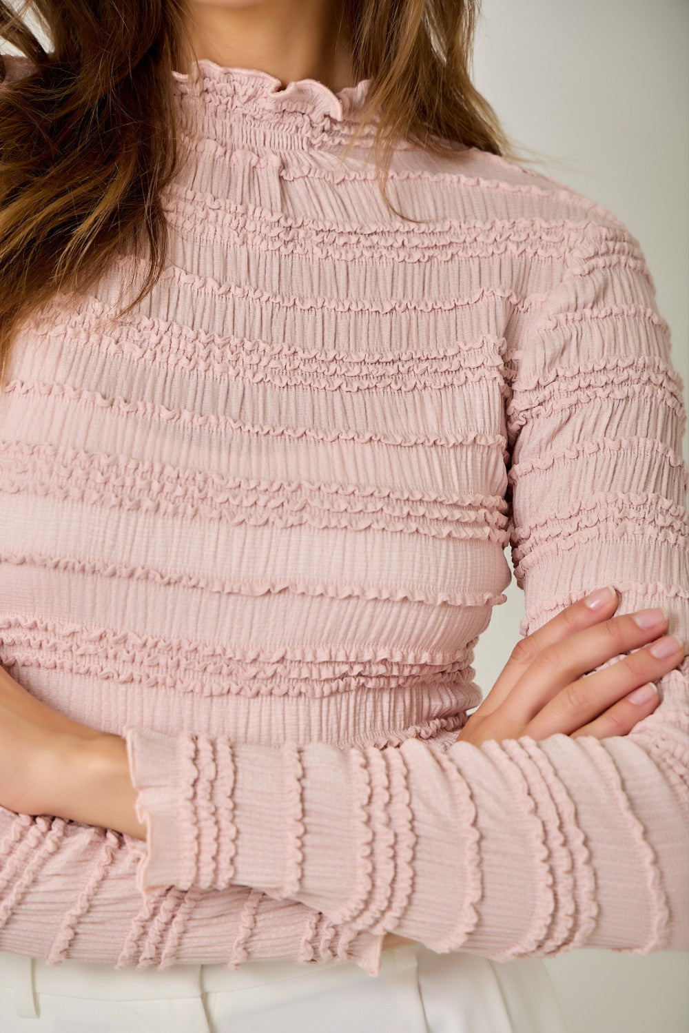 A feminine fitted knit top featuring a sleek mock neckline, long sleeves, and playful ruffled lettuce-edge stripes for a flattering statement look.
