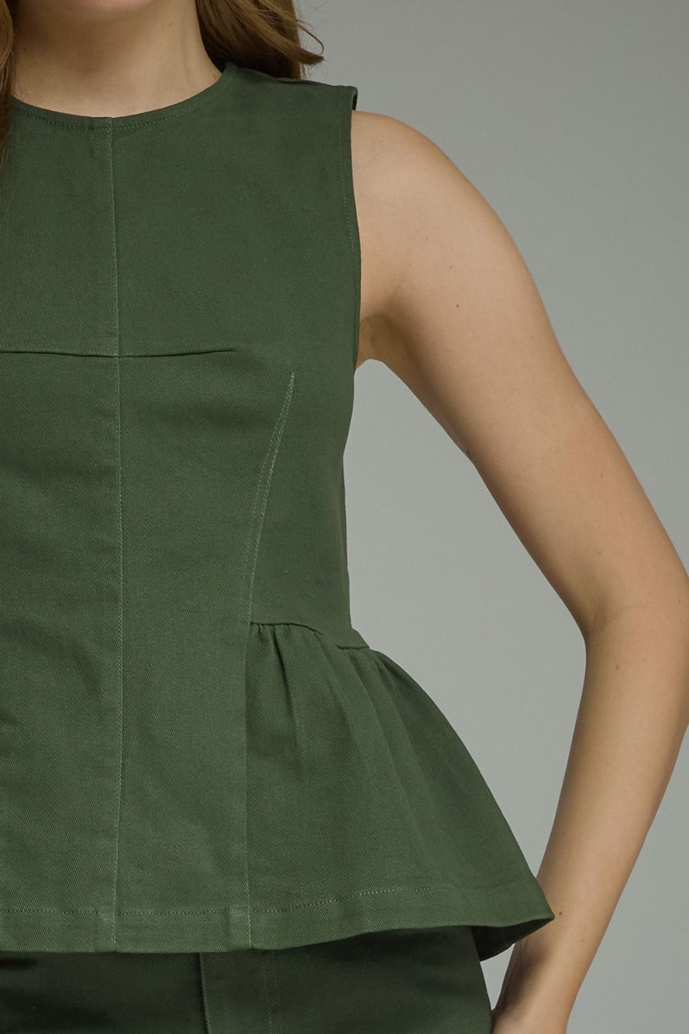 A timeless sleeveless peplum top featuring a flattering silhouette, clean lines, and lightweight woven fabric for effortlessly polished style.