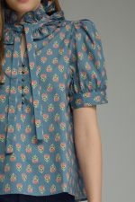 printed puff sleeve blouse features a feminine ruffle neckline, self-tie detail, and timeless button-front styling.
