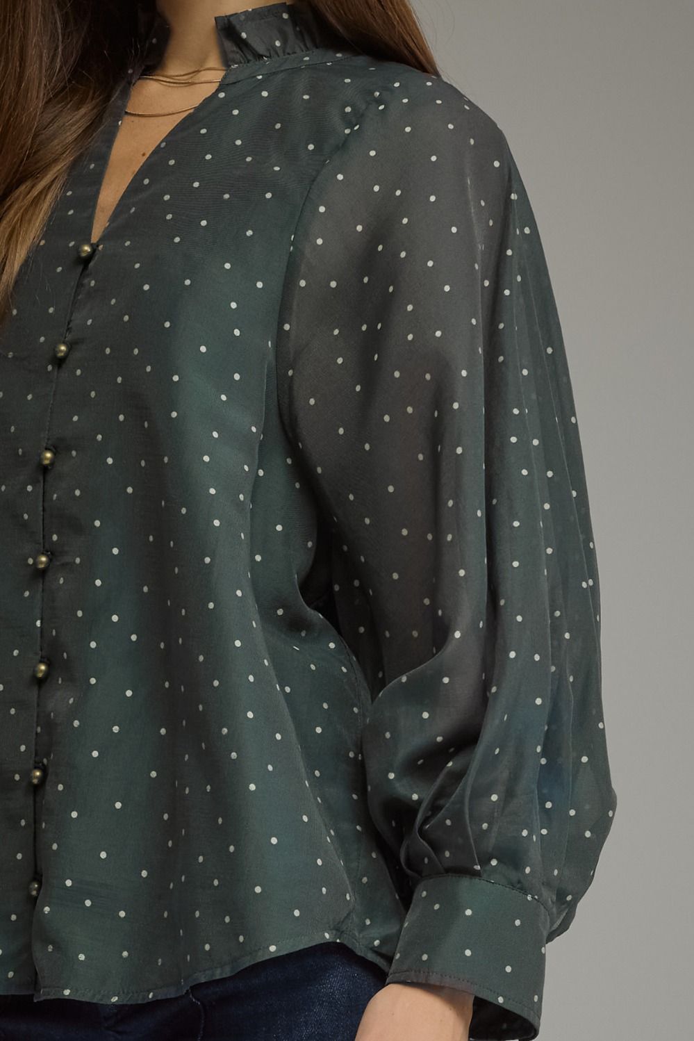 A lightweight polka dot blouse featuring a feminine ruffled neckline, button-front detail, and elegant long sleeves for effortless boutique style.