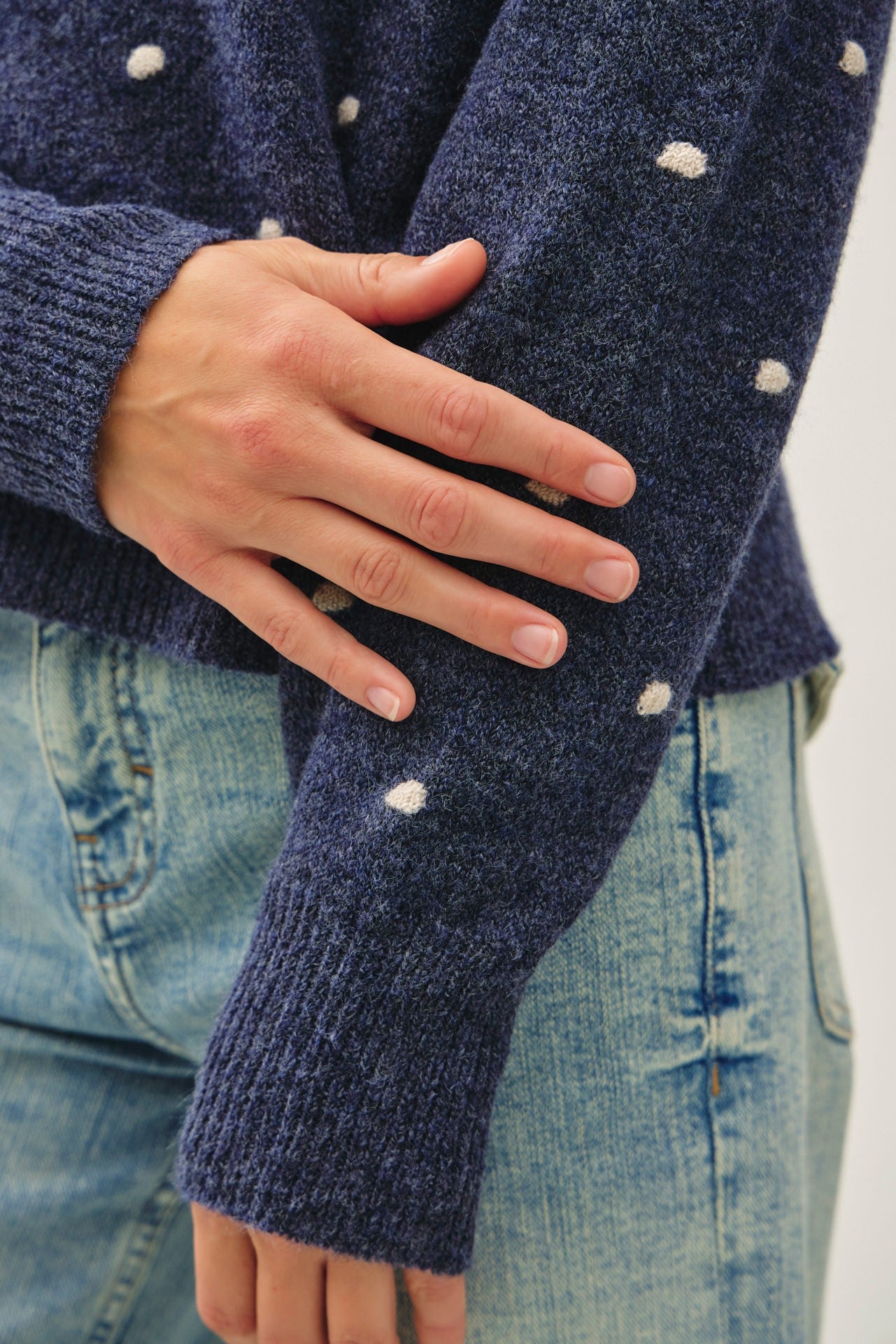 Close-up of a navy blue knit sweater with small white polka dots 