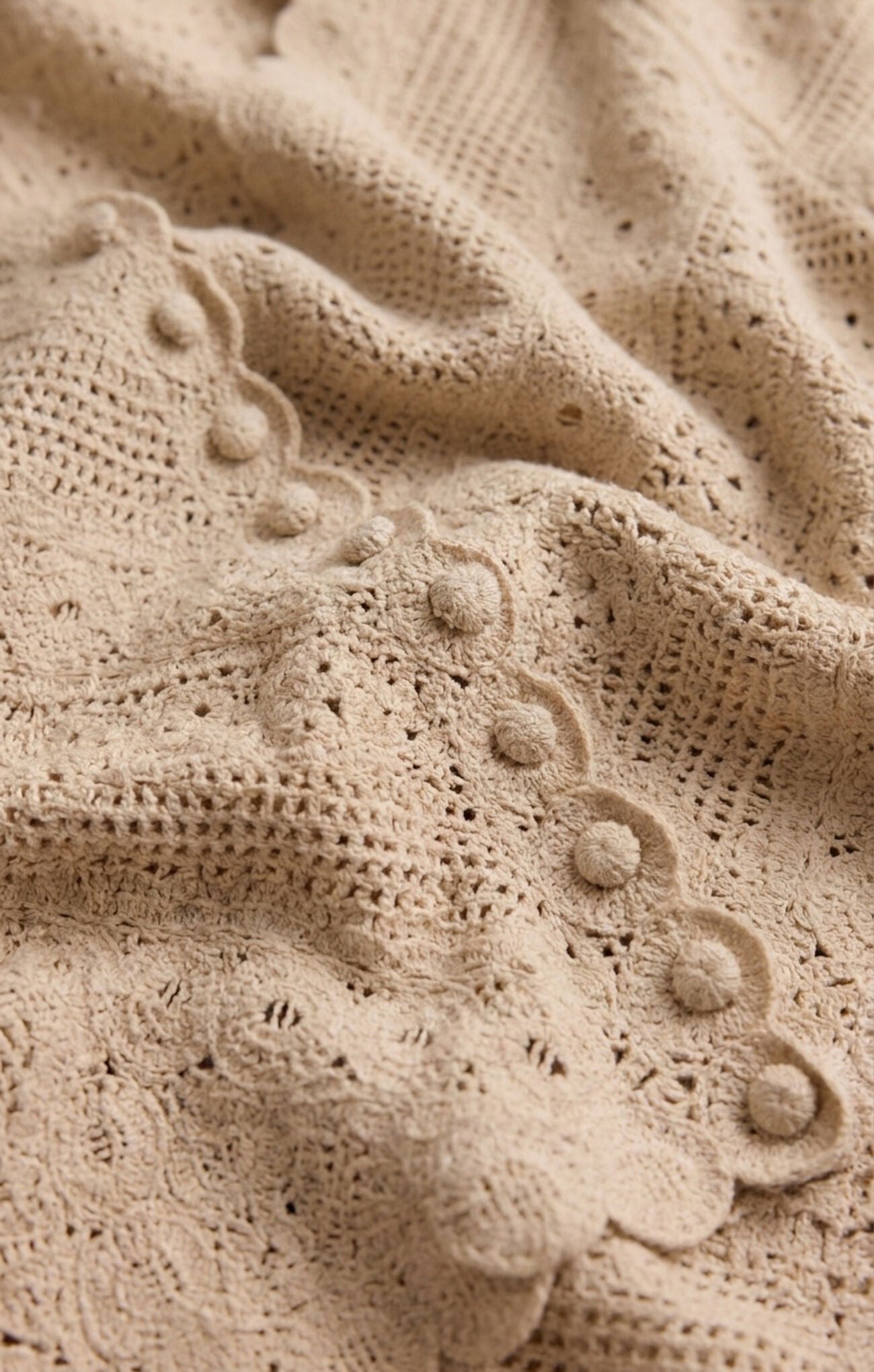 a beige crochet cardigan with crew neckline and covered buttons,long sleeves 