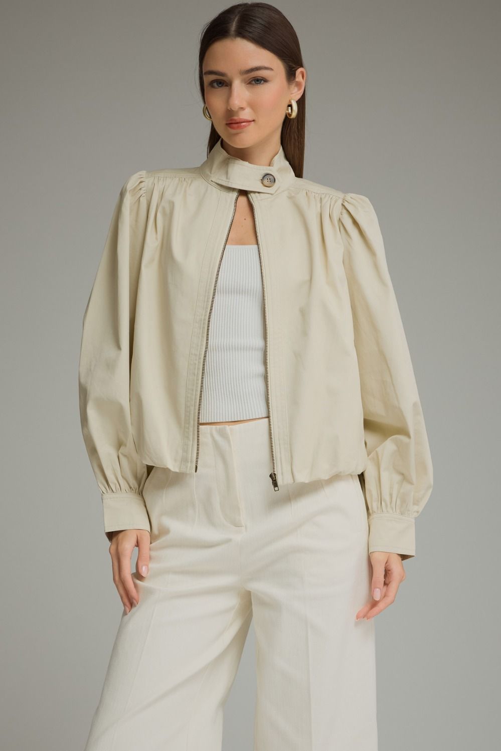 A polished everyday jacket featuring dramatic puff sleeves, a structured stand collar with a unique button closure, and a flattering elastic hem.

