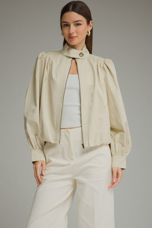 A polished everyday jacket featuring dramatic puff sleeves, a structured stand collar with a unique button closure, and a flattering elastic hem.

