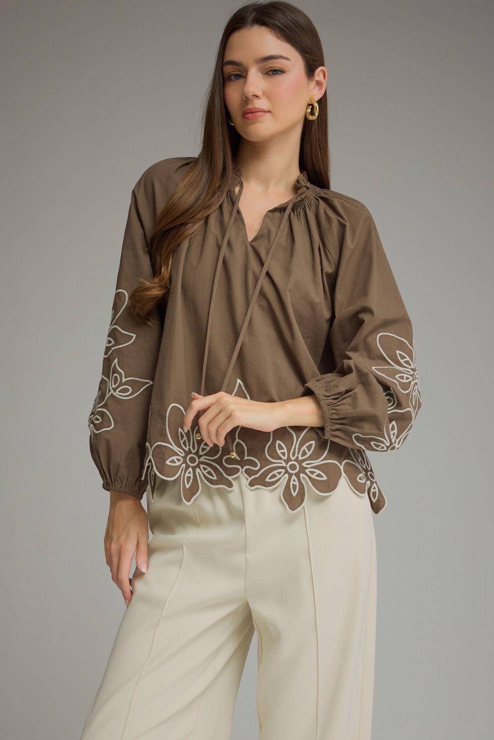 A charming lightweight woven top featuring a romantic ruffle neckline, self-tie front, and delicate embroidery for effortlessly feminine style.

