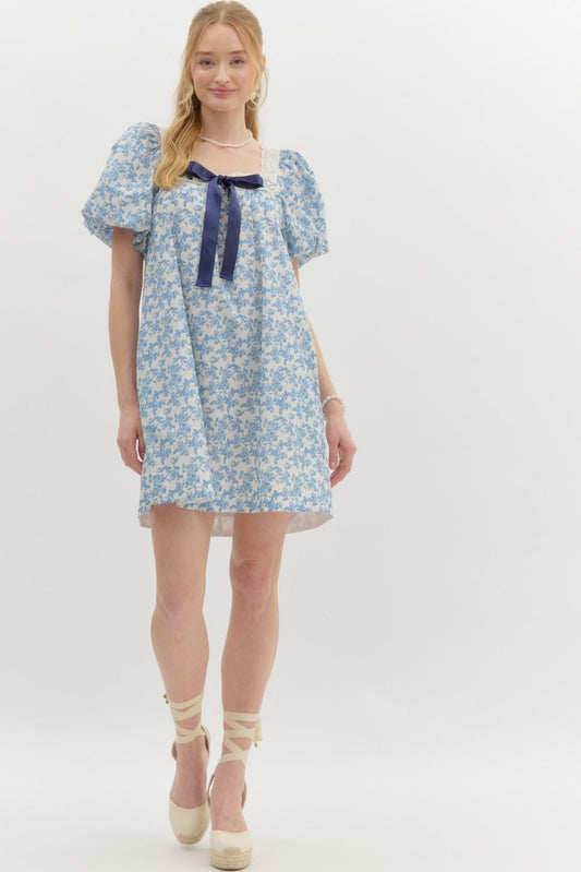  blue floral print puff sleeve dress with lace trim and a navy ribbon bow.