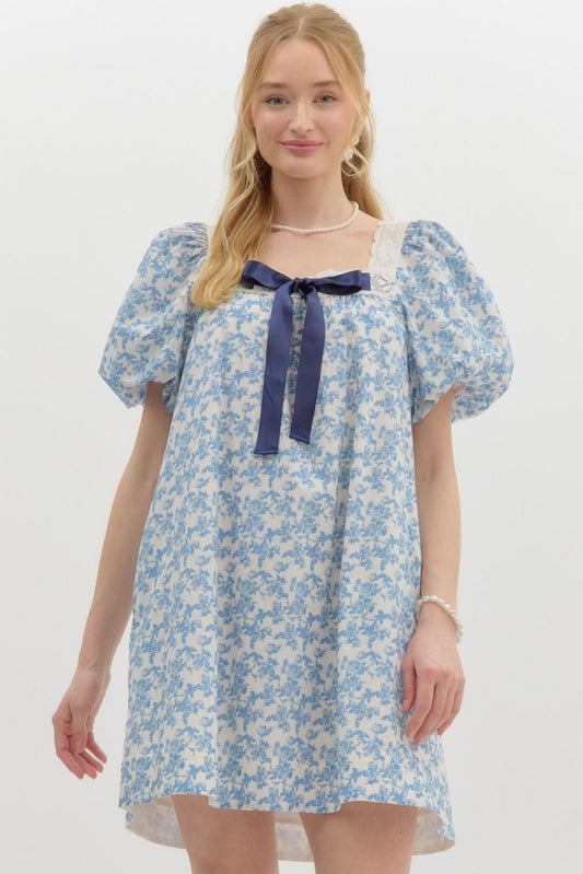  blue floral print puff sleeve dress with lace trim and a navy ribbon bow.