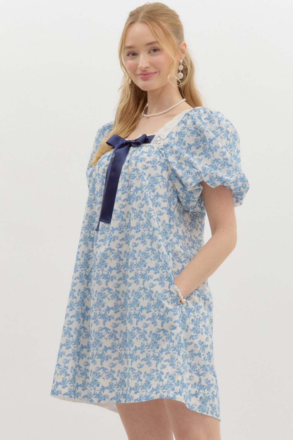  blue floral print puff sleeve dress with lace trim and a navy ribbon bow.