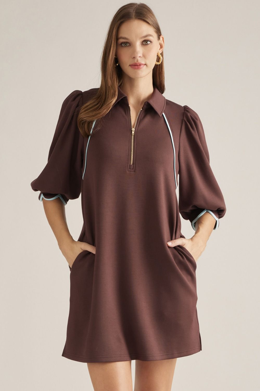 Solid knit mini dress with three-quarter puff sleeves, contrast piping, front zipper, scalloped cuffs, and side pockets