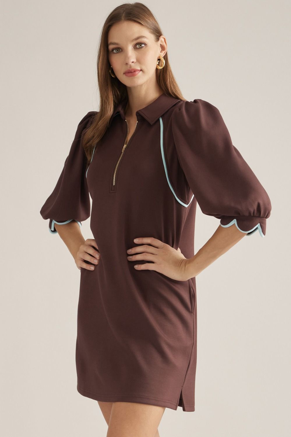 Solid knit mini dress with three-quarter puff sleeves, contrast piping, front zipper, scalloped cuffs, and side pockets