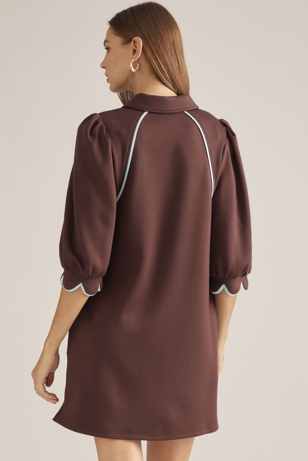 Solid knit mini dress with three-quarter puff sleeves, contrast piping, front zipper, scalloped cuffs, and side pockets
