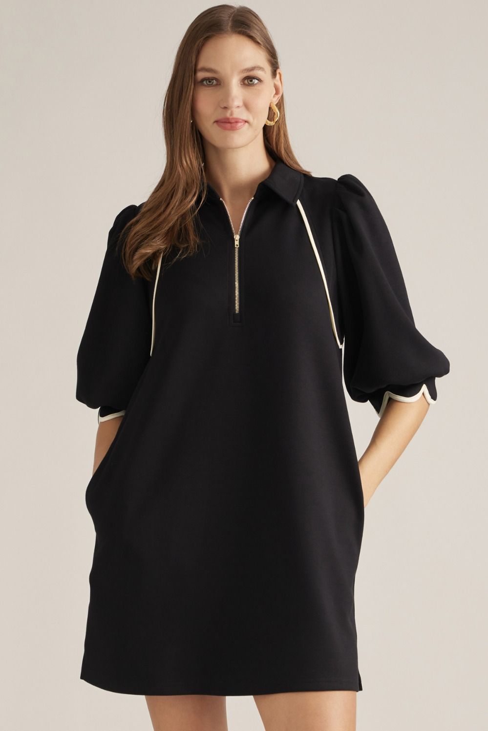 Solid knit mini dress with three-quarter puff sleeves, contrast piping, front zipper, scalloped cuffs, and side pockets