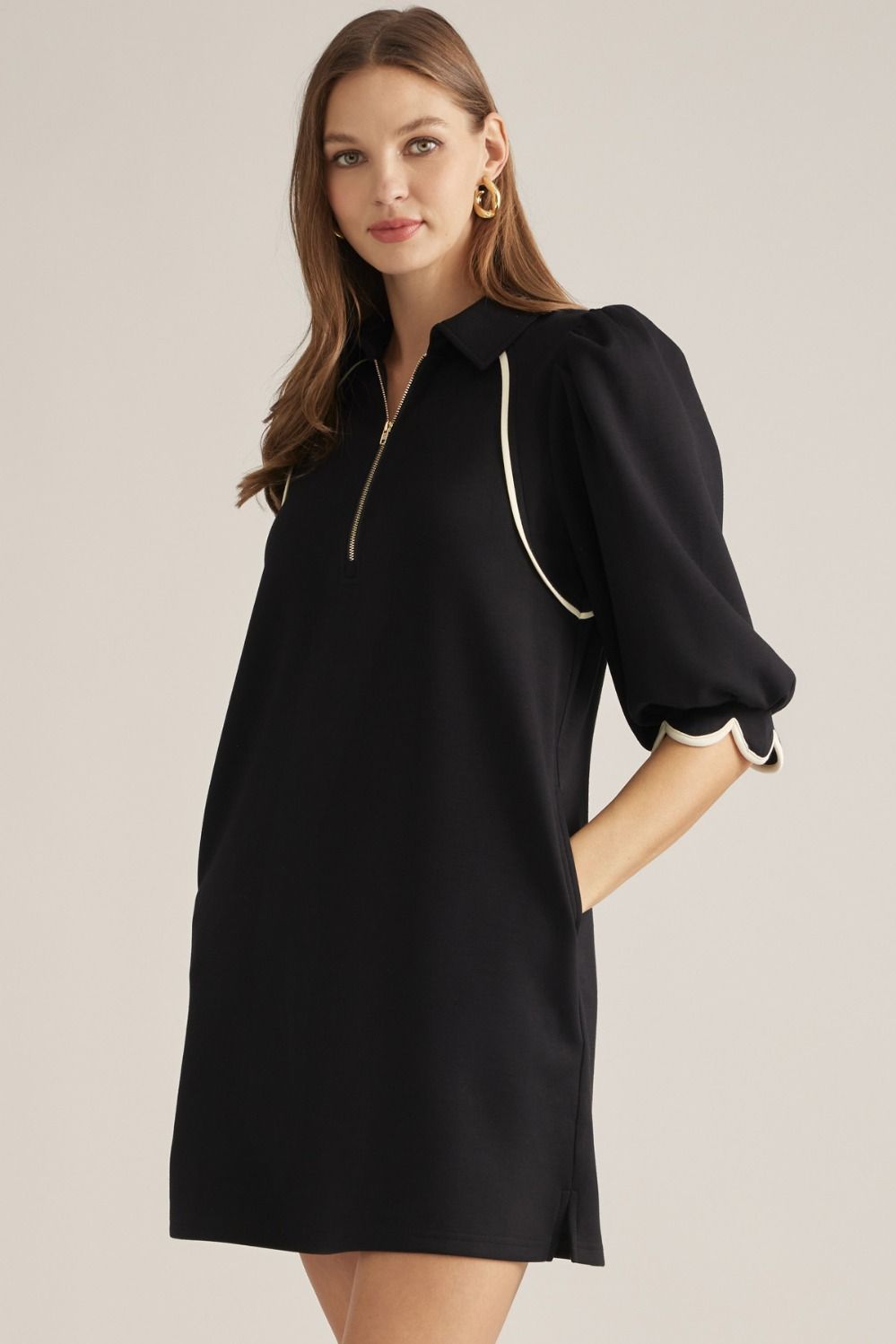 Solid knit mini dress with three-quarter puff sleeves, contrast piping, front zipper, scalloped cuffs, and side pockets