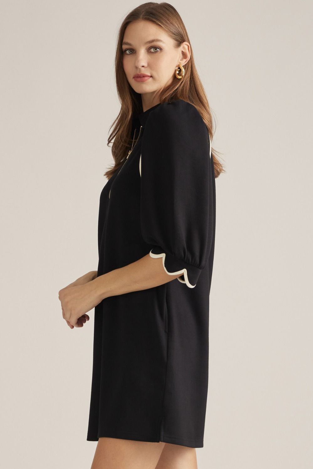 Solid knit mini dress with three-quarter puff sleeves, contrast piping, front zipper, scalloped cuffs, and side pockets