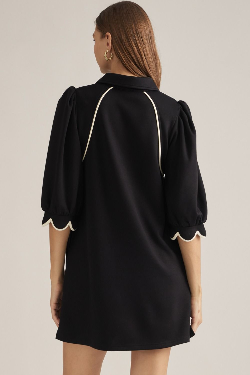 Solid knit mini dress with three-quarter puff sleeves, contrast piping, front zipper, scalloped cuffs, and side pockets