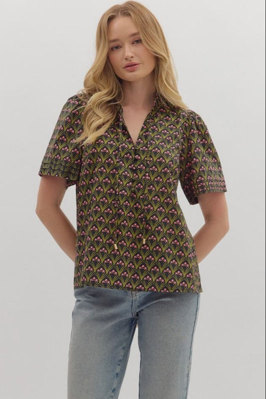 The Evangeline top combines bold geometric print with a chic ruffled mock neck and adjustable tie-front detail.