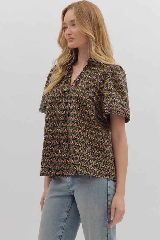 The Evangeline top combines bold geometric print with a chic ruffled mock neck and adjustable tie-front detail.