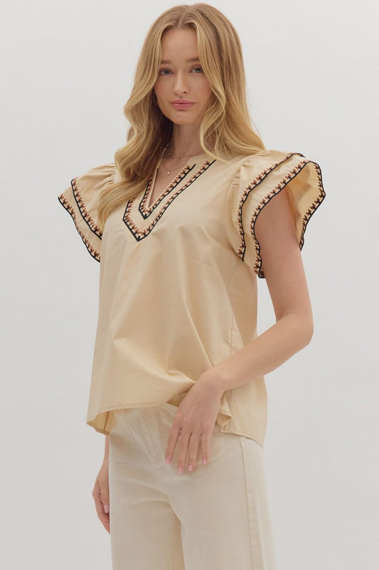 Feminine and breezy, the Odette top features layered flutter sleeves, a V-neck, and contrast embroidered trim for a polished finish.