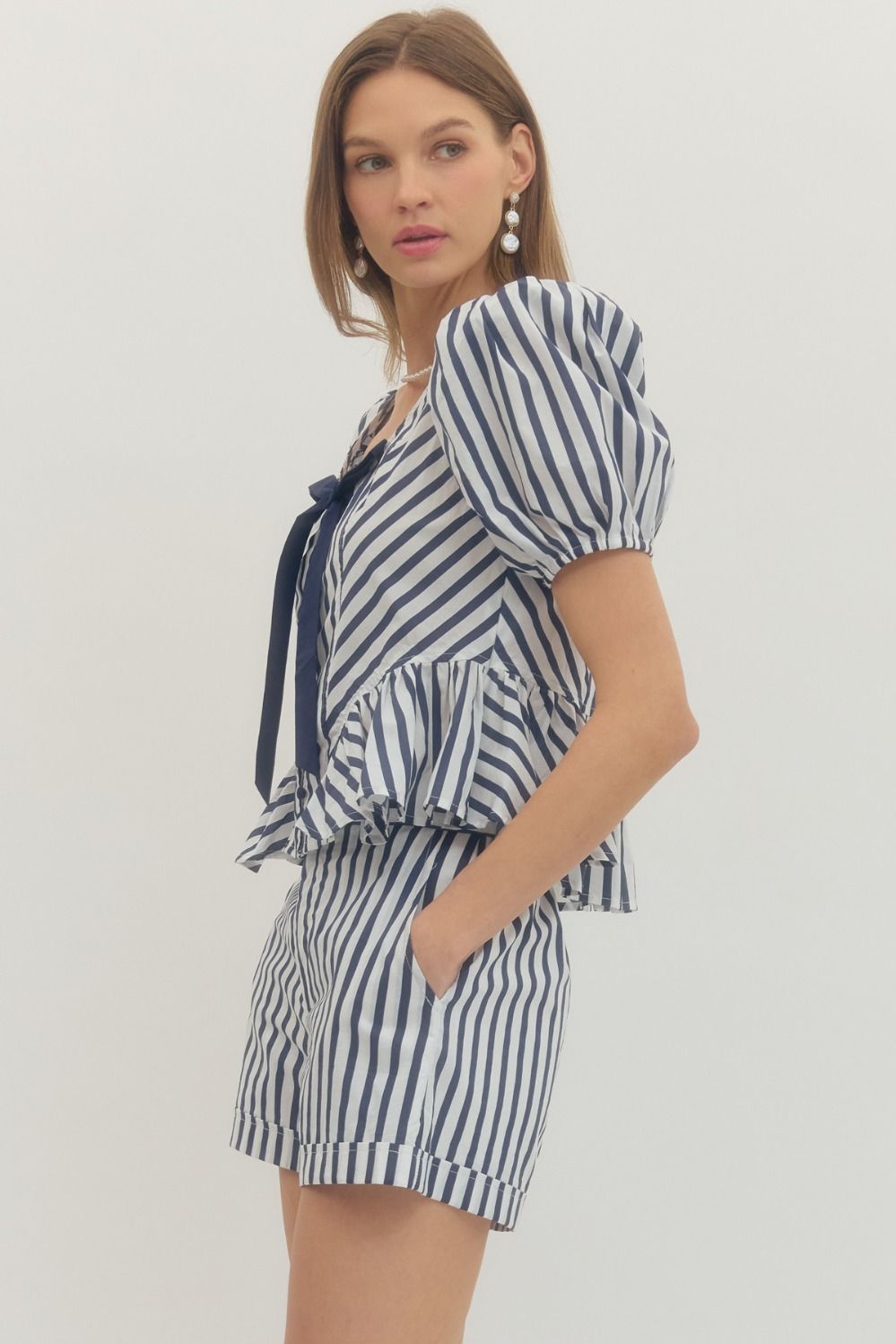 Stripe print puff sleeve peplum top with front self-tie bow detail and fabric-covered buttons.